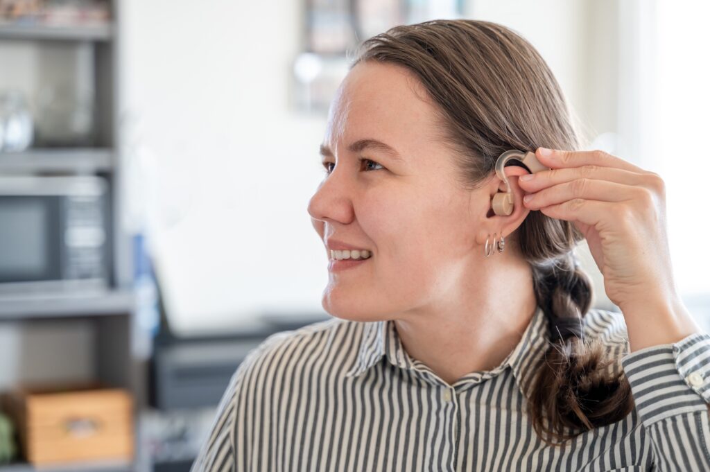 Woman applying hearing aid to ear
